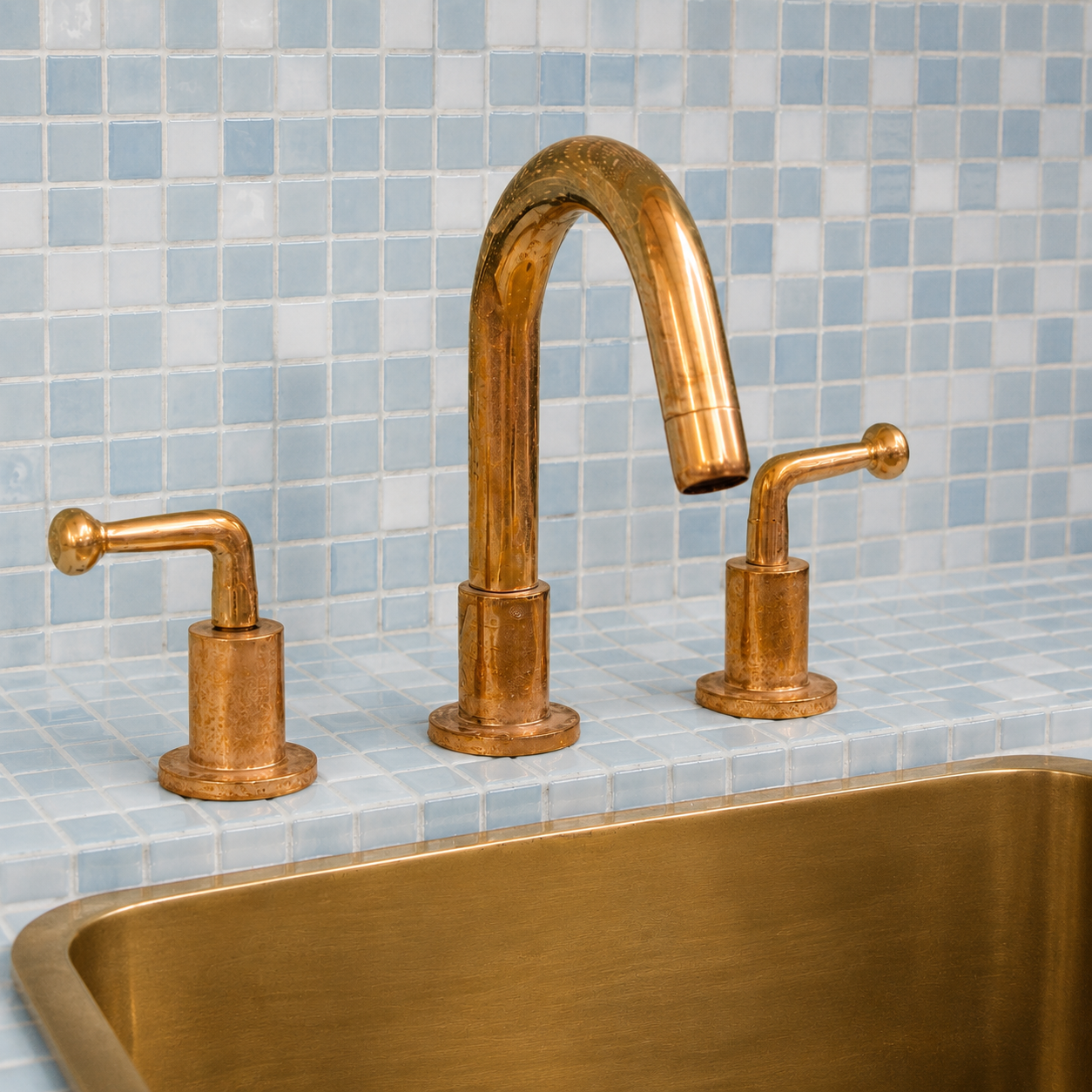 Angled view of solid unlacquered brass widespread bathroom sink faucet with lever handles