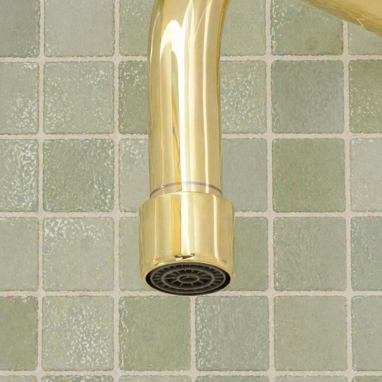 Handmade solid brass wall-mounted pot filler faucet with a swiveling neck and unlacquered living brass finish installed above a kitchen stove.