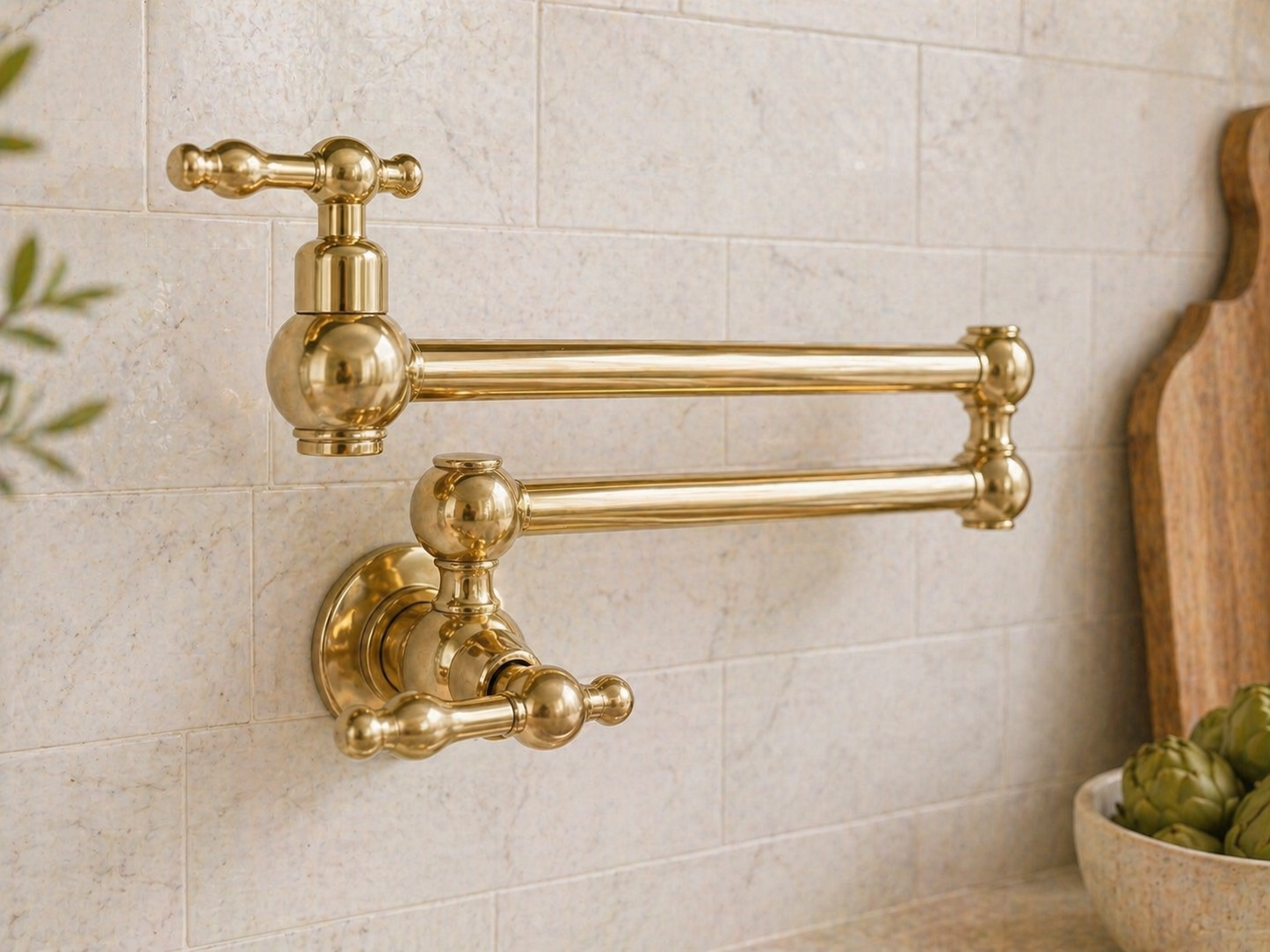 Handmade solid brass wall-mounted pot filler faucet with dual swing arms and unlacquered living brass finish installed above a kitchen stove.
