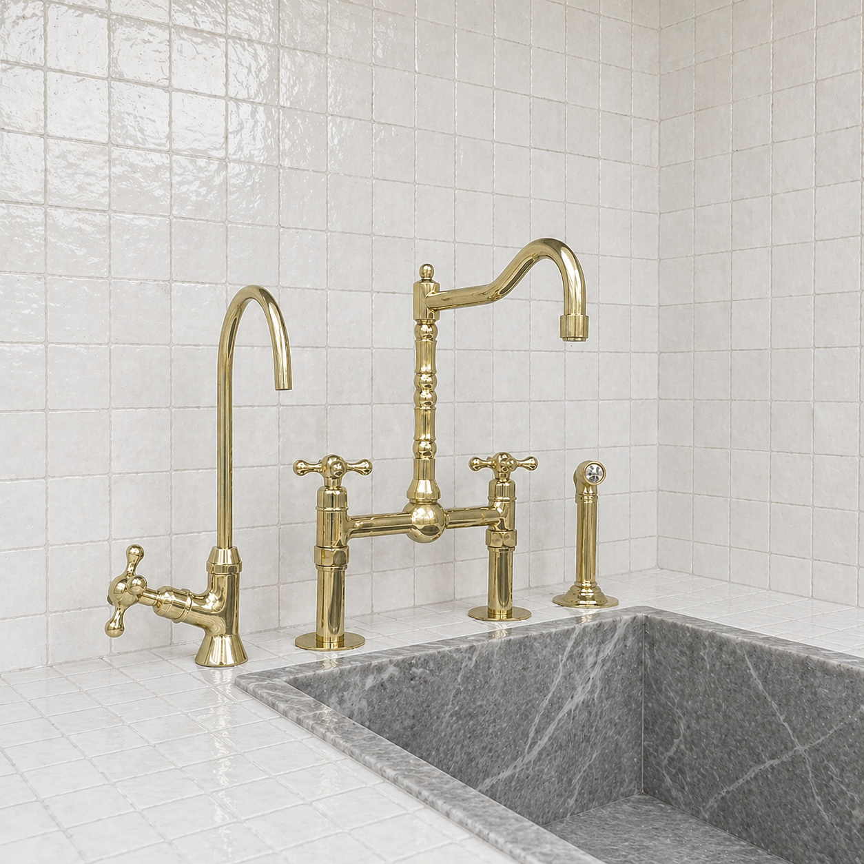 An antique brass bridge faucet set with a tall gooseneck spout, separate hot and cold handles, and a matching side faucet, installed above a gray marble sink against a white tiled wall.