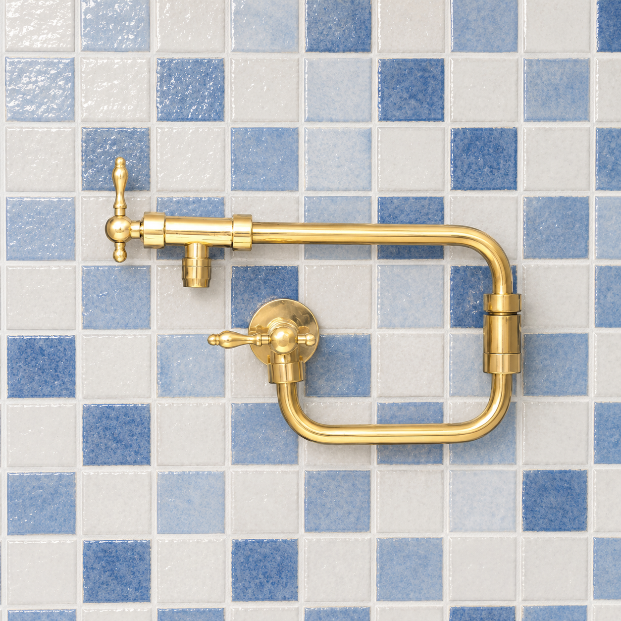 Handcrafted unlacquered solid brass wall mounted pot filler kitchen faucet with dual lever handles installed against blue tile backsplash