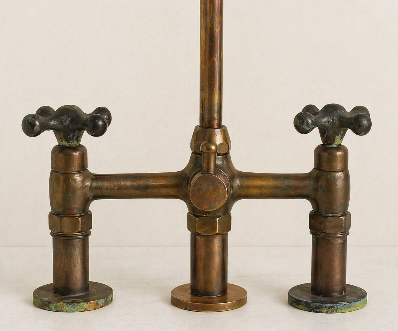 Close-up of aged brass bridge faucet body, cross handles and natural patina finish