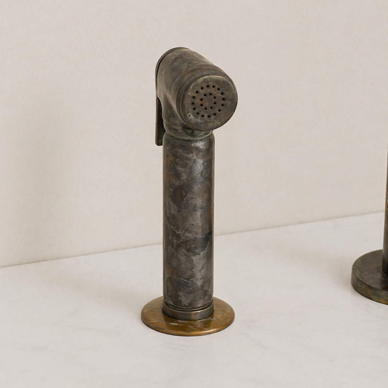 Close-up of aged brass kitchen faucet side sprayer with a natural patina finish