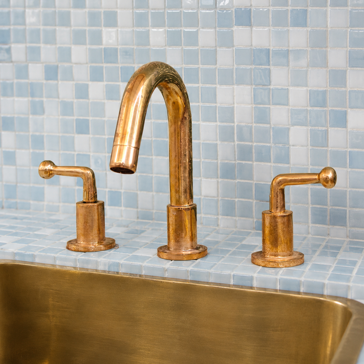 Luxury bathroom featuring a handmade unlacquered brass widespread faucet with blue zellige tiles
