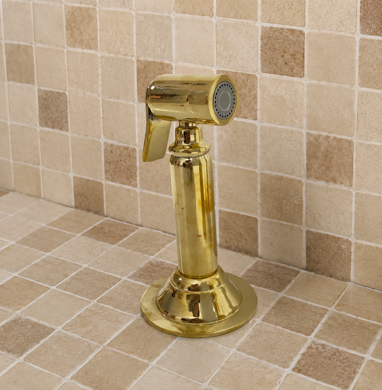Handmade solid brass kitchen side sprayer with unlacquered finish and shut-off handle installed beside a kitchen faucet.