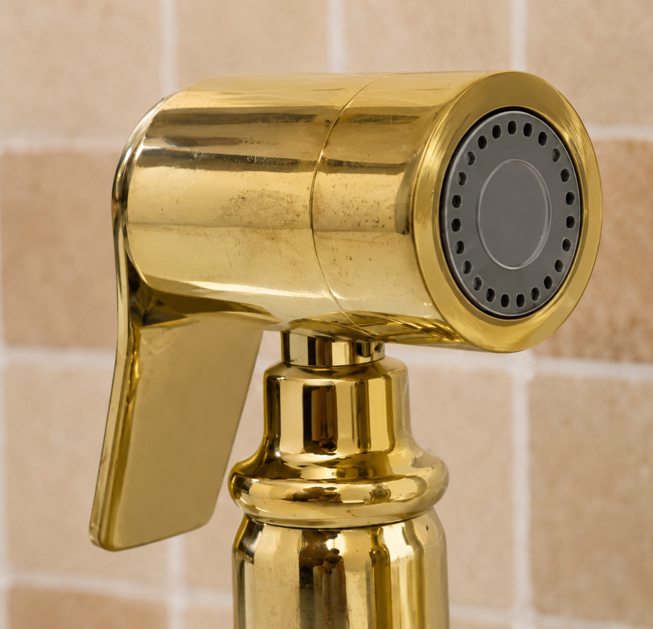 Handmade solid brass kitchen side sprayer with unlacquered finish and shut-off handle installed beside a kitchen faucet.