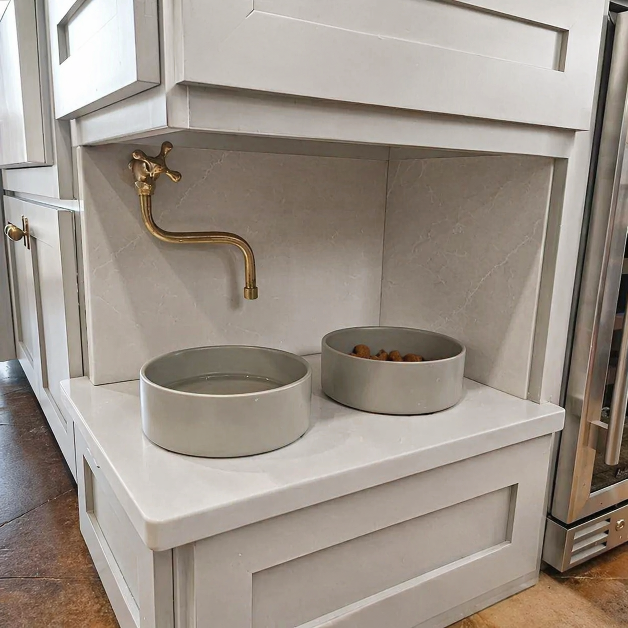 Handmade solid brass wall-mounted pot filler faucet with a swiveling neck and unlacquered living brass finish installed above a kitchen stove.