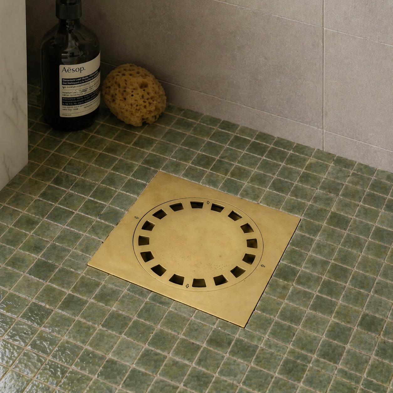 Handmade solid brass square shower floor drain with an unlacquered finish installed in a tiled shower floor.