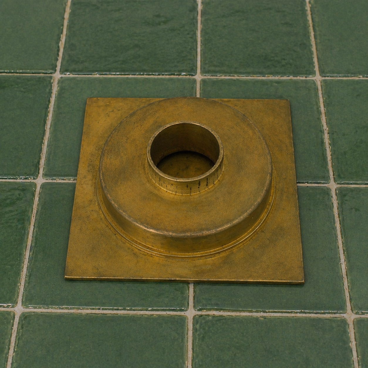 Handmade solid brass square shower floor drain with an unlacquered finish installed in a tiled shower floor.