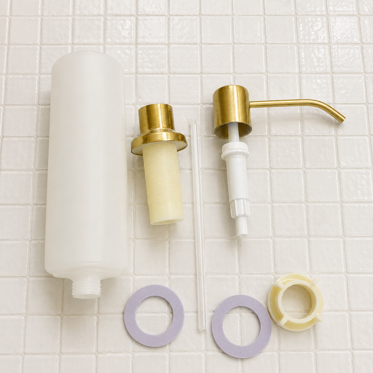 Handcrafted solid brass built-in sink soap dispenser installed on a countertop beside a brass kitchen sink.